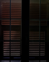 Light that filters between the closed shutters - obrazy, fototapety, plakaty