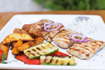 Grilled chicken with grilled vegetables on white plate.