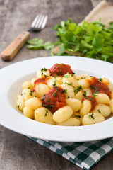 Gnocchi with tomato sauce on wooden background

