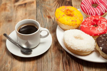 Cup with coffee and donuts on a wooden background