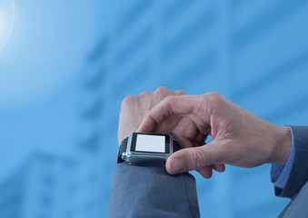Businessman holding watch against blue buildings