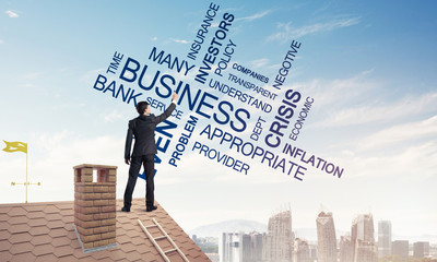 Young businessman standing on house roof and writing leadership 
