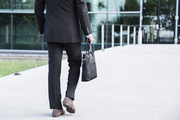 Businessman or worker standing in suit near office building