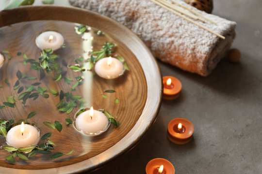 Beautiful spa composition with green leaves and candles on water