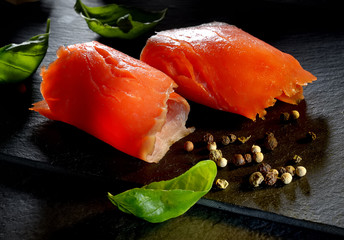 Roll slice of salmon, basil on black slate
