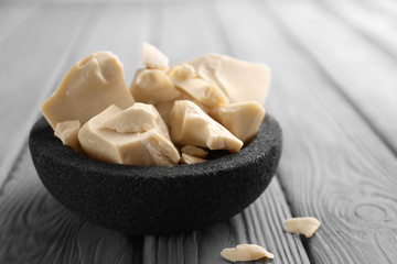 Bowl with cocoa butter on wooden table