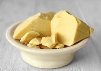Bowl with cocoa butter on wooden background