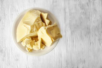 Bowl with cocoa butter on wooden background