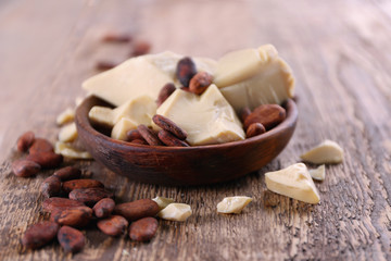 Bowl with cocoa butter and beans on wooden table