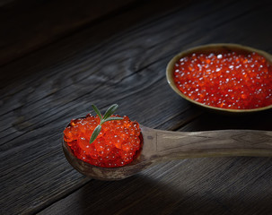 Red caviar in spoon on aged wooden background