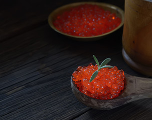 Red caviar in spoon on aged wooden background