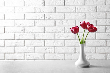 Vase with beautiful tulips on table