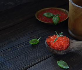 Red caviar in spoon on aged wooden background