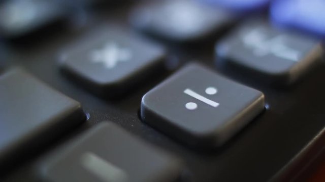 Division on a calculator device. Finger press on division button calculator