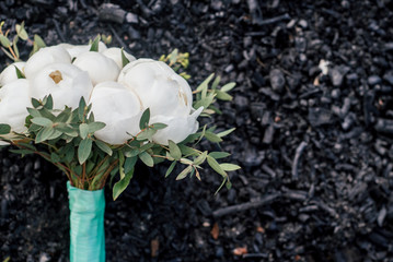 Wedding bouquet of white peonies on black charcoa, selective focus. Bridal bouquet of peony, free space