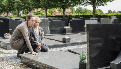 mother and daughter at grave of deceased father