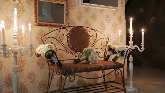 Bouquets on a bench on the background of wedding decorations. On the sides of the candles in candlesticks