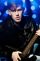 Fototapeta premium young attractive rock musician playing electric guitar and singing. Rock star on background of spotlights