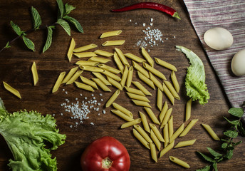 Pasta and other products on the table. Pepper, tomato, salt, penne, eggs. Top View