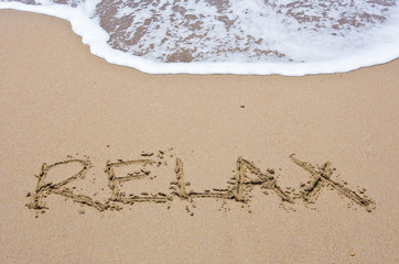 The word "relax" on the sand of the beach