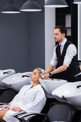 The attractive male master washes the girl's head in the beauty salon