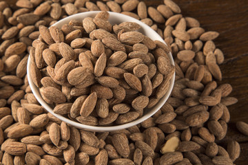 Almonds in white bowl on wooden background