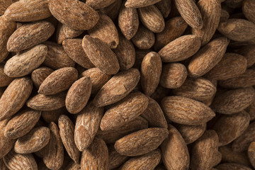 Almonds in brown bowl on wooden background