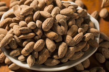 Almonds in white bowl on wooden background