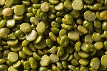 Green lentils in wooden bowl on wood background. Edible raw pulses of the legume family.