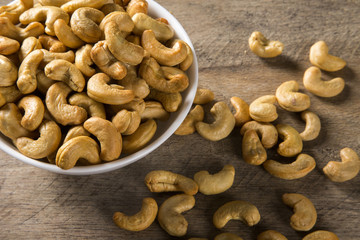 Cashew nuts in white bowl on wood background