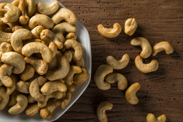 Cashew nuts in white bowl on wood background