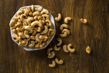 Cashew nuts in white bowl on wood background