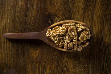 walnuts in wood spoon on wood table.