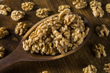 walnuts in wood spoon on wood table.