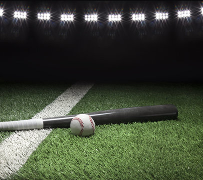 Gray baseball bat and ball on field with stadium lights