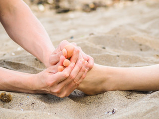 Foot massage on a beach in sand, male and female caucasian