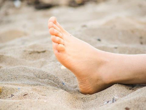 Foot of one unrecognizable caucasian person resting in sand, with no sand on foot