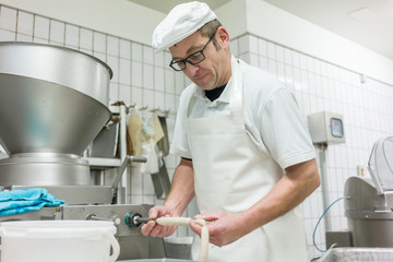 Butcher filling sausages at machine