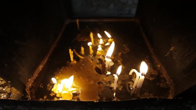 group of candles burning in a dark church ambient
