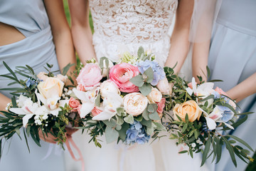 Bride and bridesmaid holding in the hands bouquets of beautiful fresh flowers - obrazy, fototapety, plakaty