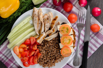 Healthy salad bowl with tomatoes, chicken on wooden background
