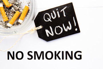 No Smoking - Quit Now - with cigarettes, ashtray and handwritten blackboard on blue background
