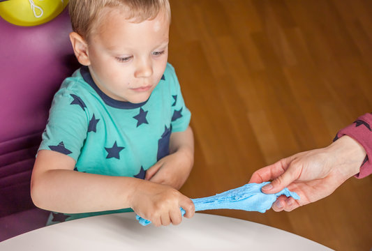 cute boy stretching big blue piece of plasticine