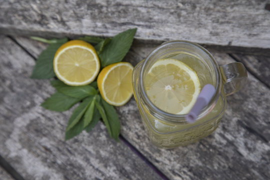 Lemon juice in jar, decorated with fresh lemons and mint leaves.