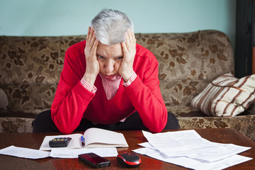 Senior old woman desperate over the bills she has to pay, worried and with headache