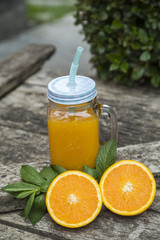 Obraz na płótnie Canvas Orange juice in jar, decorated with fresh oranges and mint leaves.