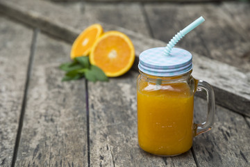 Orange juice in jar, decorated with fresh oranges and mint leaves.