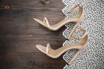 Beige sandals with a high heel on a white lace background