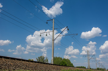 High-voltage wire along railway under blue sky