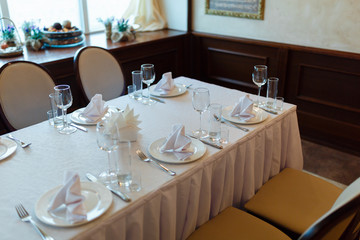 Plate with fork, knife and napkin served on the wedding table, all ready for the holiday.